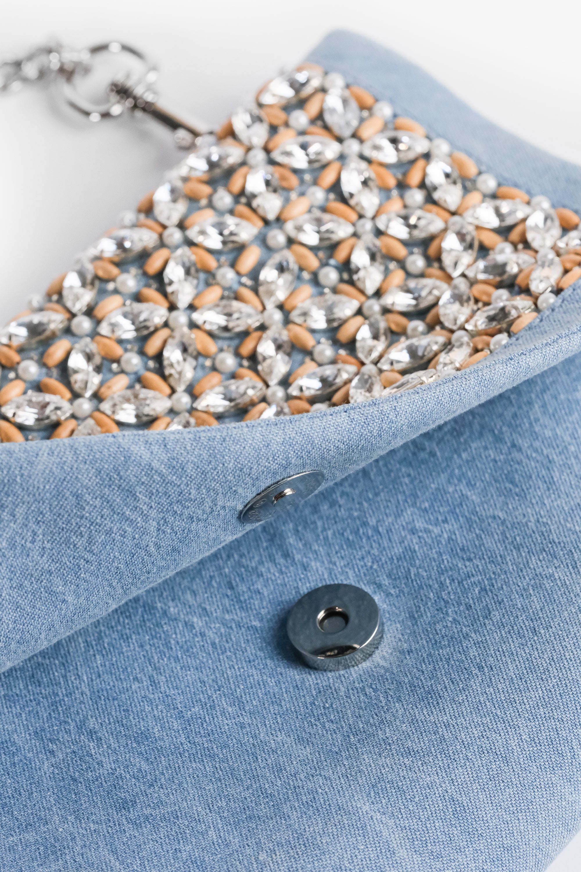 Acambha's Crystal Bead Glam Clutch features delicate crystal beading, pearls, and wooden beads, with a zipper and magnet button on the flap. This clutch showcases meticulous craftsmanship.