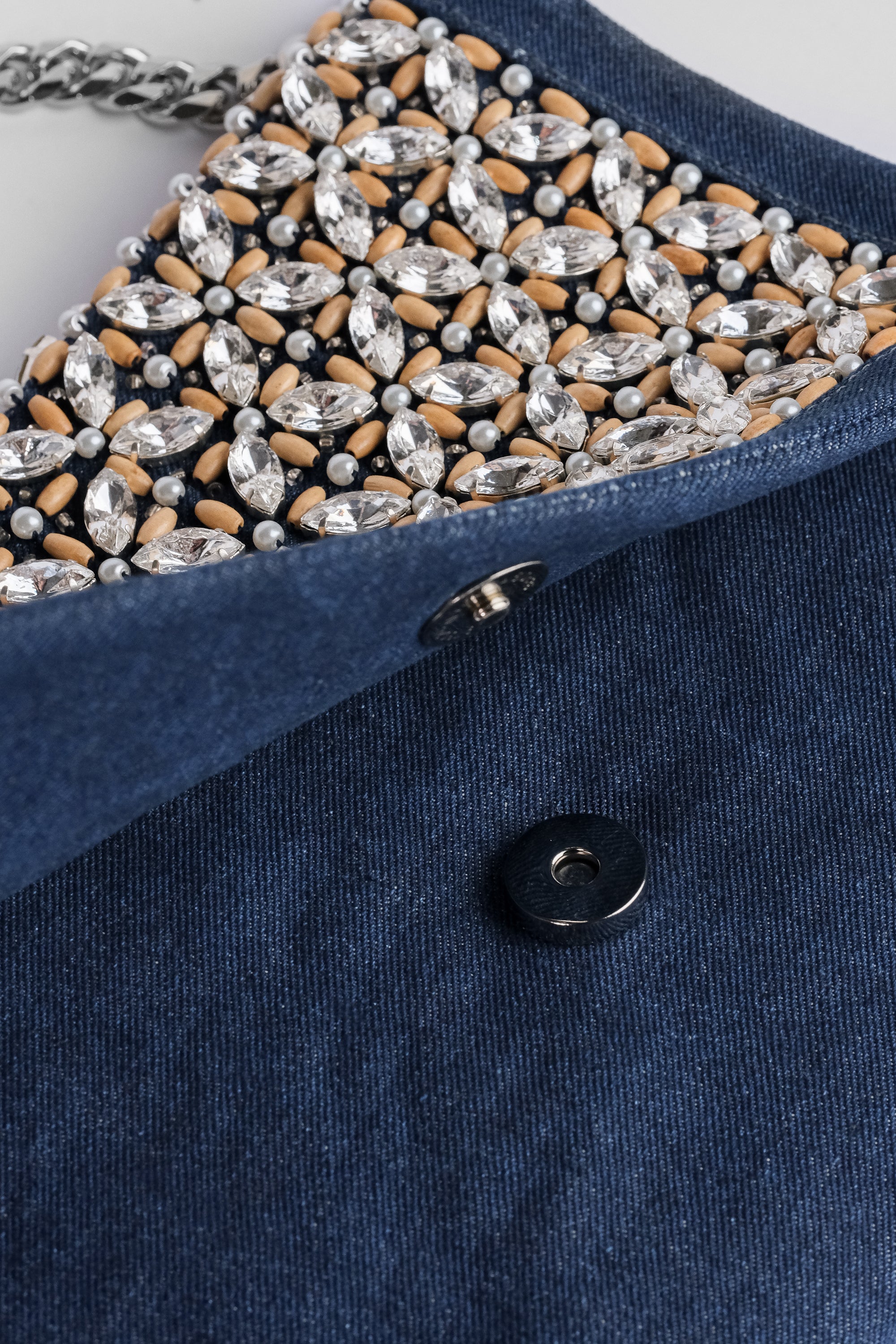 Acambha's Crystal Bead Glam Clutch features delicate crystal beading, pearls, and wooden beads, with a zipper and magnet button on the flap. This clutch showcases meticulous craftsmanship.