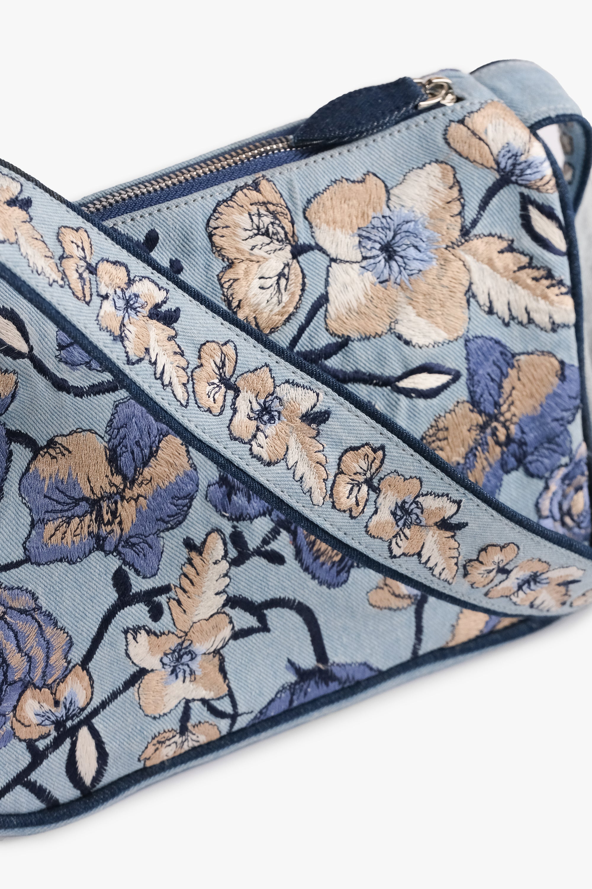 Acambha's Embroidered Denim Shoulder Bag, featuring multi-colored embroidery on light denim. Meticulous craftsmanship, extending from the body to the strap. Framed with dark blue piping.