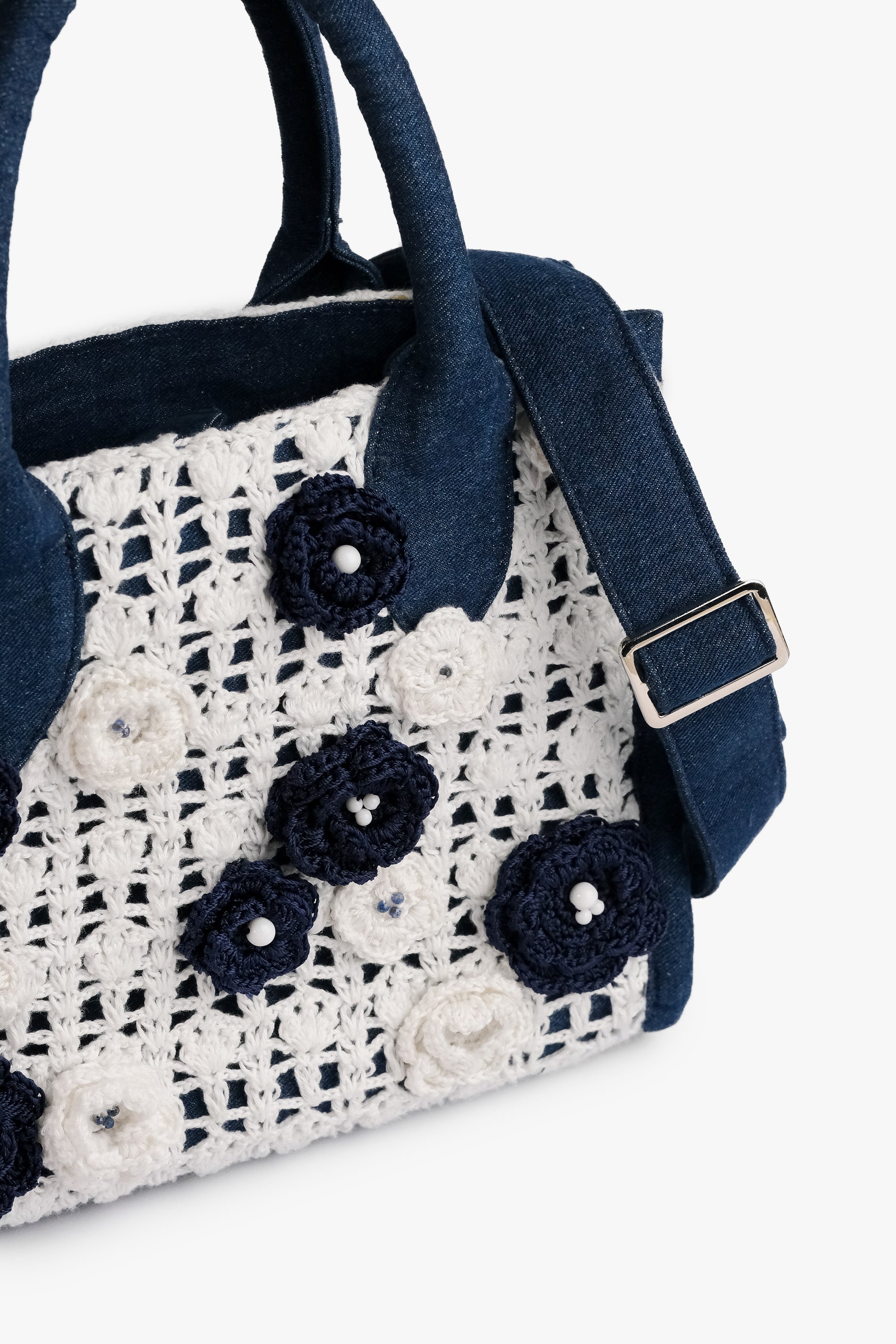 Acambha Crochet Tote, handcrafted with a crochet panel featuring delicate flowers on sturdy dark blue denim. Combines traditional charm with modern chic, showcasing skilled artisan craftsmanship.