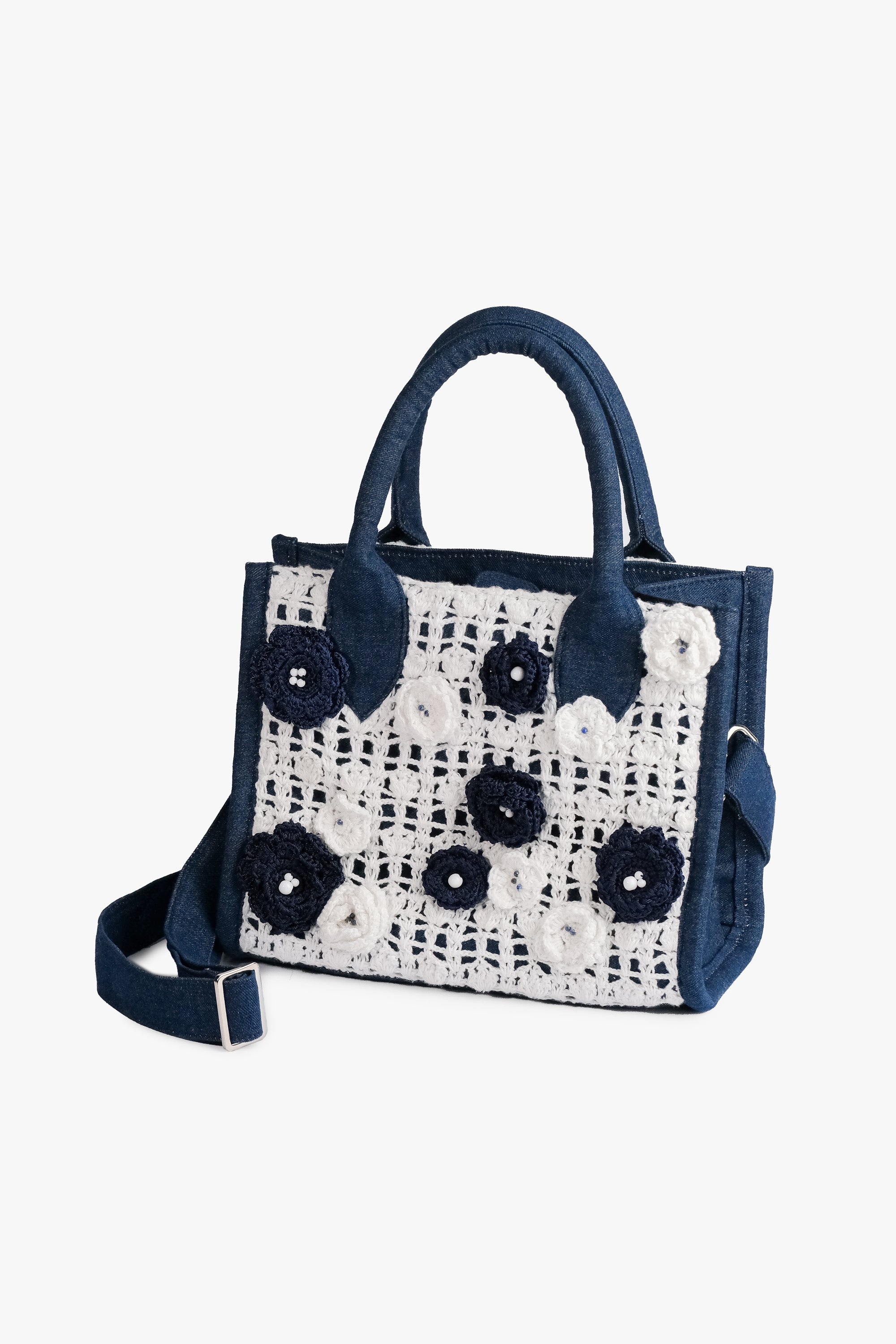 Acambha Crochet Tote, handcrafted with a crochet panel featuring delicate flowers on sturdy dark blue denim. Combines traditional charm with modern chic, showcasing skilled artisan craftsmanship.